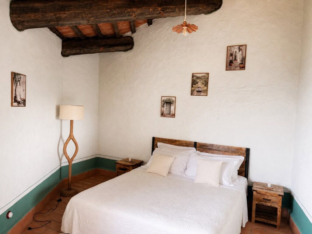 Bedroom with a double bed and framed photos in the Il belvedere apartment, Borgo Braila, Umbria