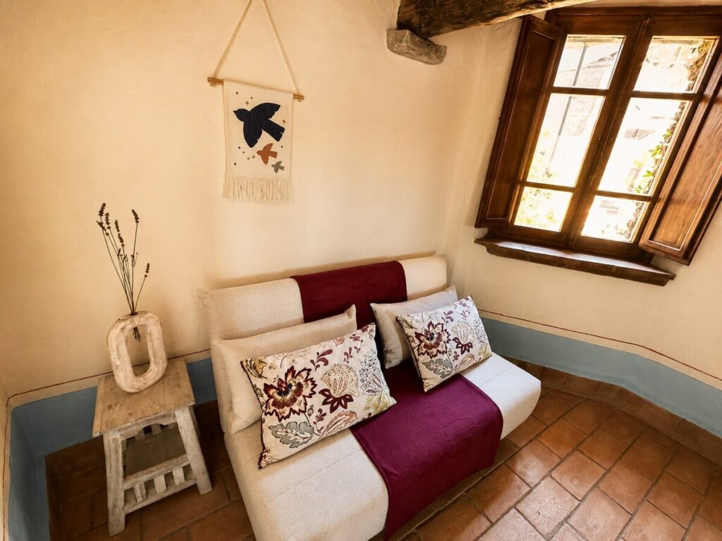 Loft bedroom with a sofa bed and window in the Il belvedere apartment, Borgo Braila, Umbria