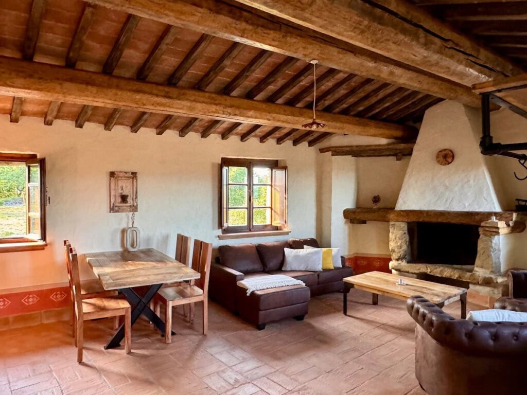 Living room with fireplace and rustic dining table in the Il cavaliere apartment, Borgo Braila, Umbria