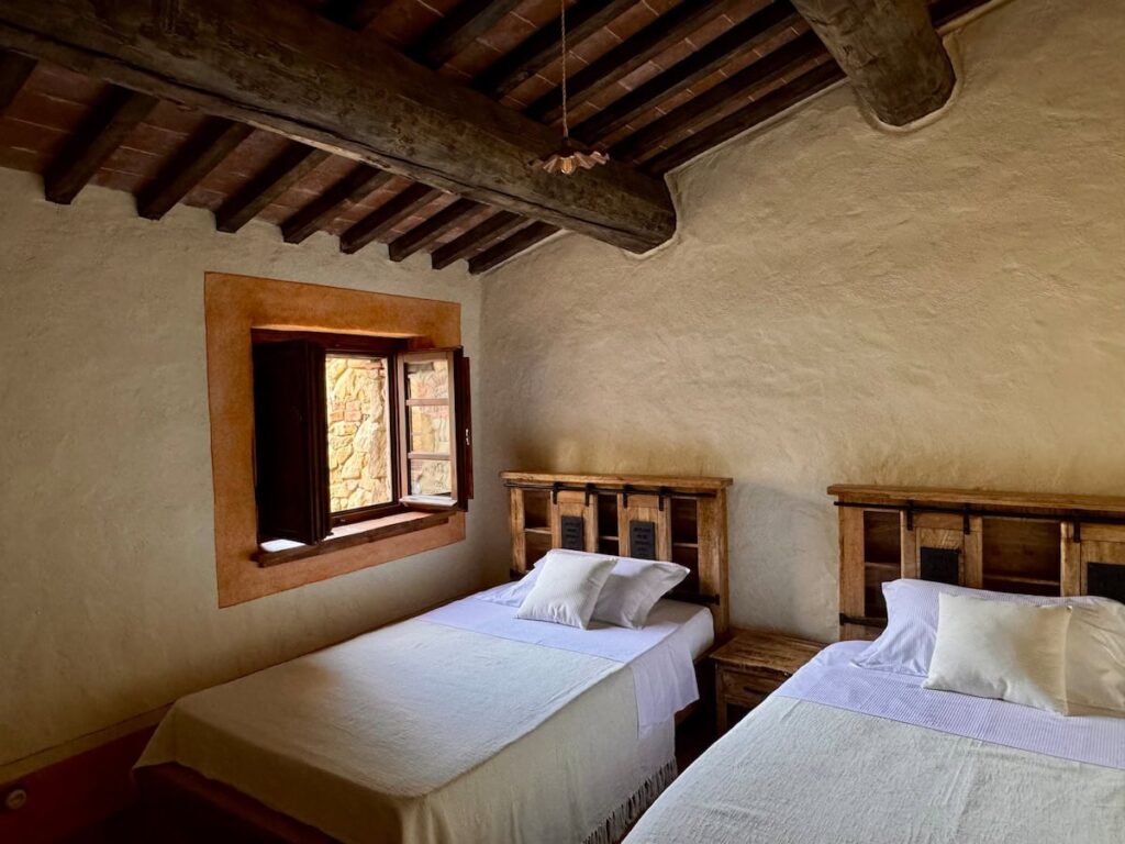 Bedroom with exposed beamed ceiling and window in the Il cavaliere apartment, Borgo Braila, Umbria