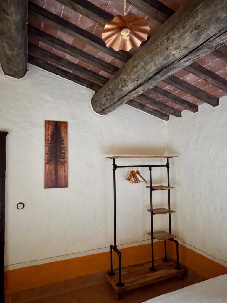 Bedroom detail with a wooden clothes valet in the Il cavaliere apartment, Borgo Braila, Umbria