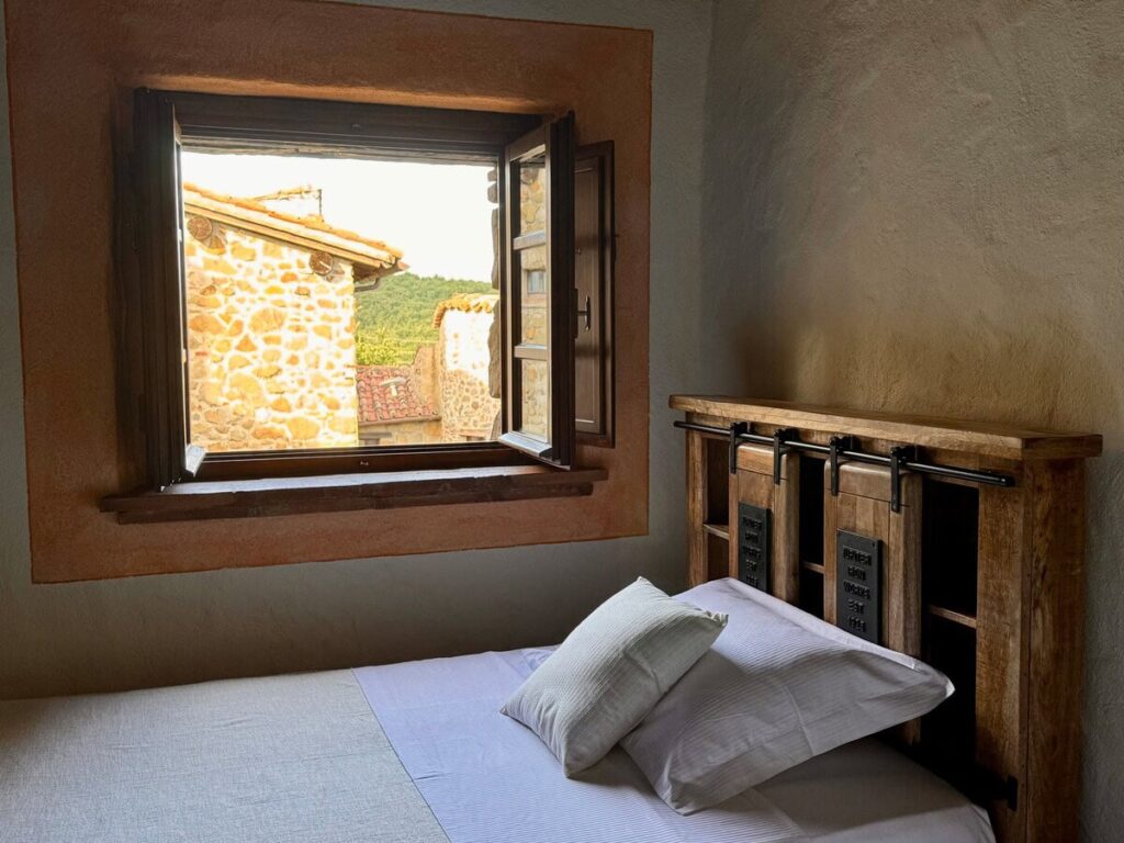 Bedroom with an open window and stone view in the Il cavaliere apartment, Borgo Braila, Umbria