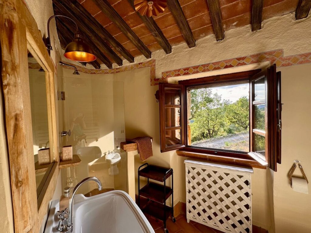 Bathroom with a bathtub beneath a panoramic window in the Il cavaliere apartment, Borgo Braila, Umbria