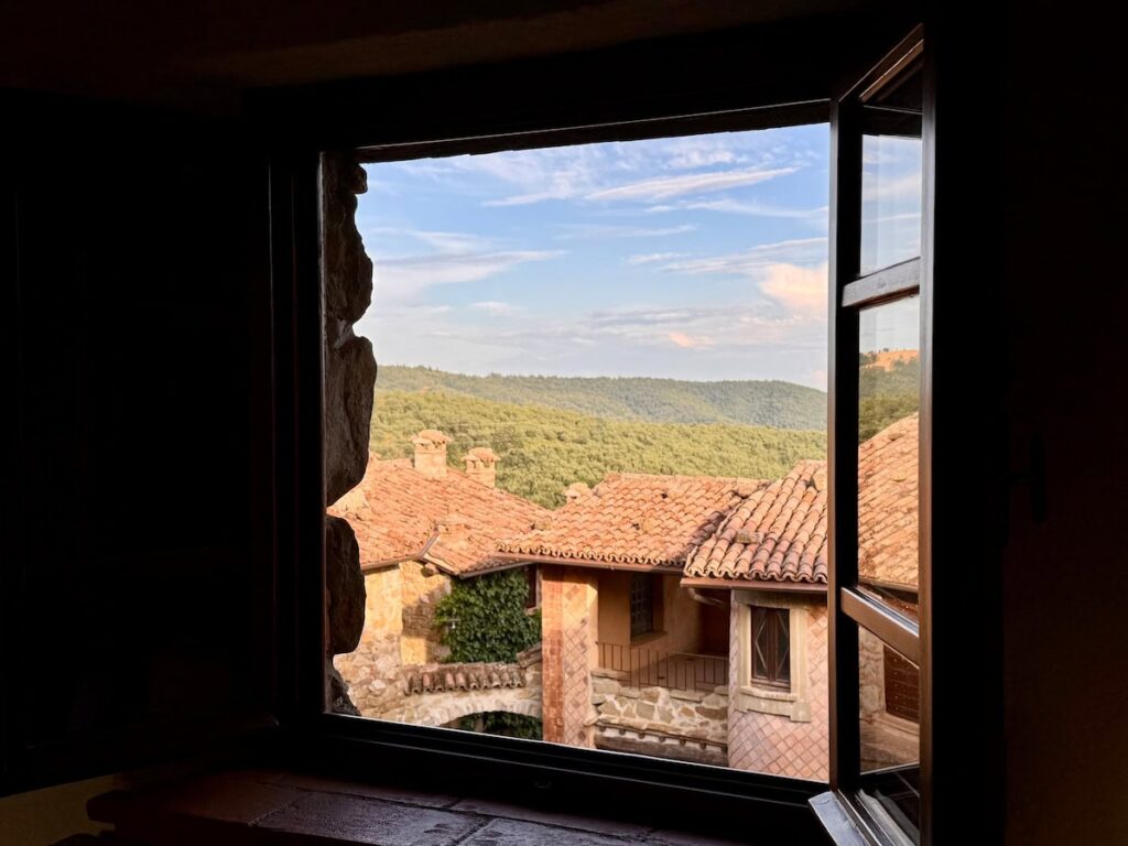 Open window with a panoramic view of the village and Umbrian hills in the Il cavaliere apartment, Borgo Braila, Umbria