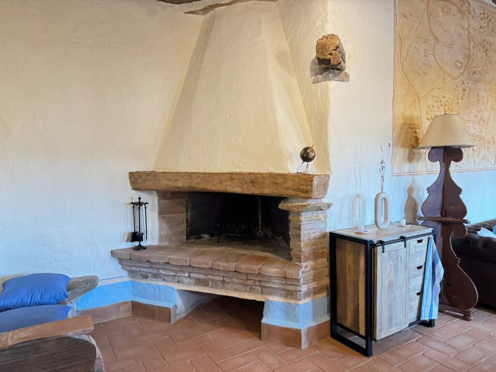 Living room with a stone fireplace in the La carta apartment, Borgo Braila, Umbria