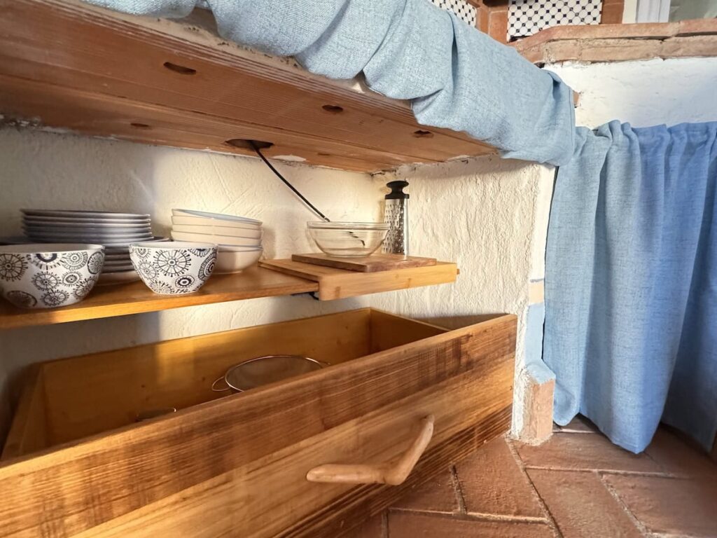 Kitchen counter with a curtained cabinet in the La carta apartment, Borgo Braila, Umbria