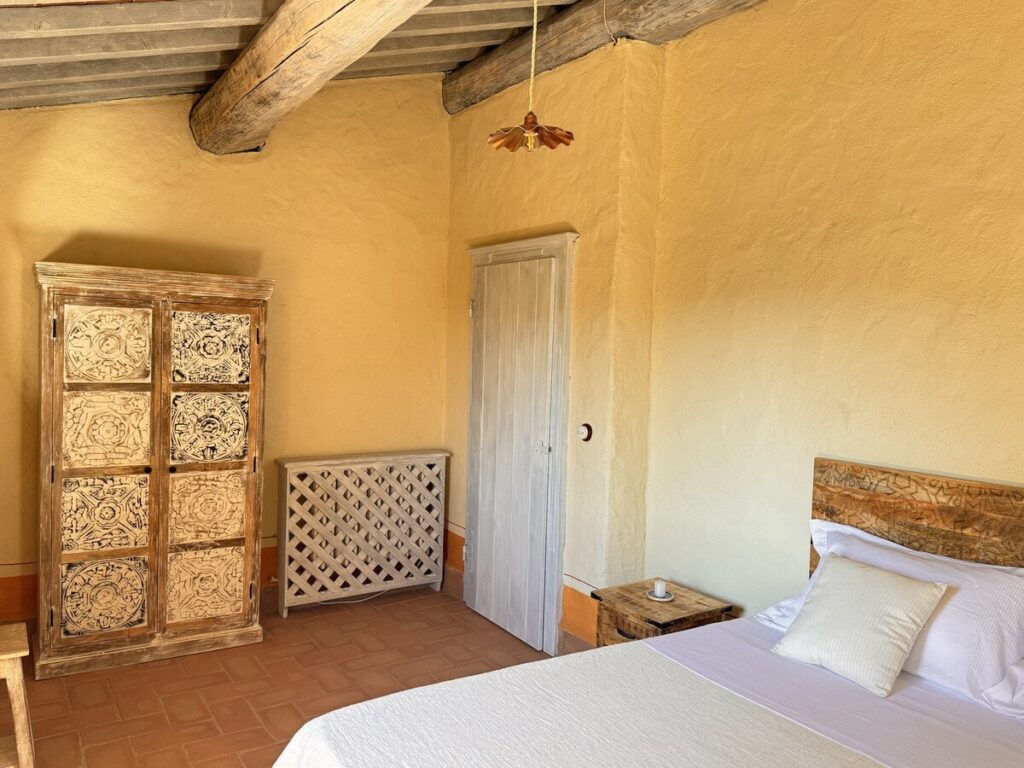 Bedroom with a wooden headboard and window in the La carta apartment, Borgo Braila, Umbria
