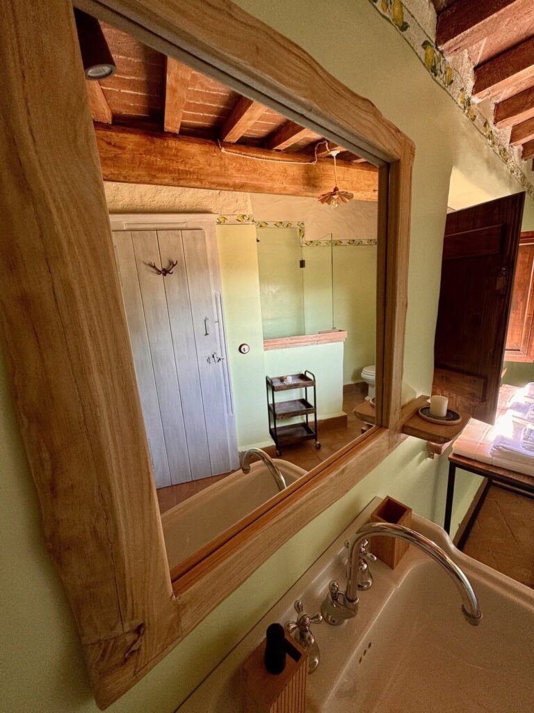 Bathroom with a mirror and shelf in the La carta apartment, Borgo Braila, Umbria
