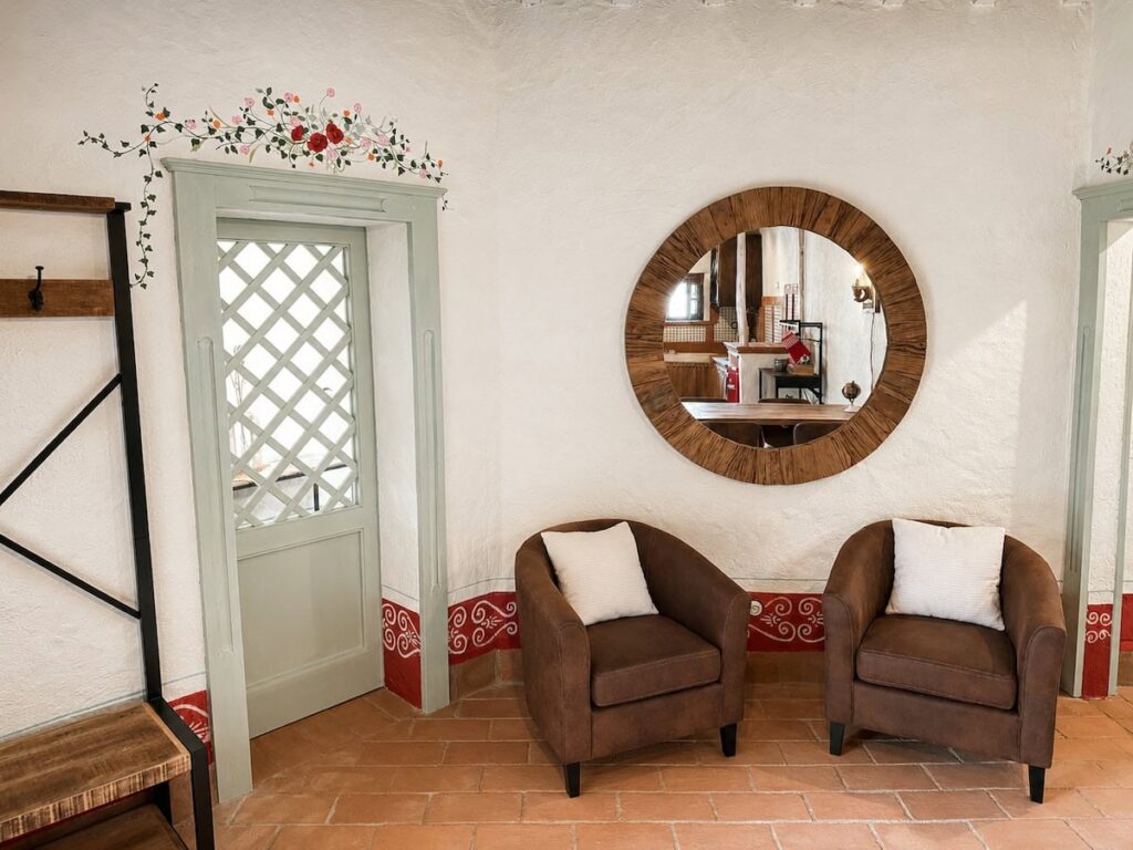 Living room with a round mirror and armchairs in the Il ponente apartment, Borgo Braila, Umbria