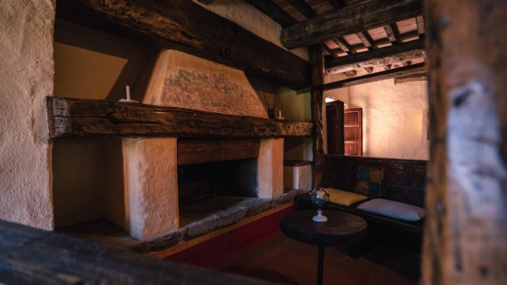 Living room with exposed beams and a stone pillar in the Il cardinale apartment, Borgo Braila, Umbria