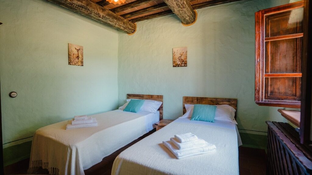 Bedroom with two beds and a window in the Il cardinale apartment, Borgo Braila, Umbria