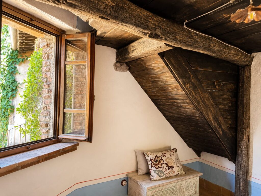 Bedroom with exposed beams and natural materials in a Borgo Braila apartment, Borgo Braila