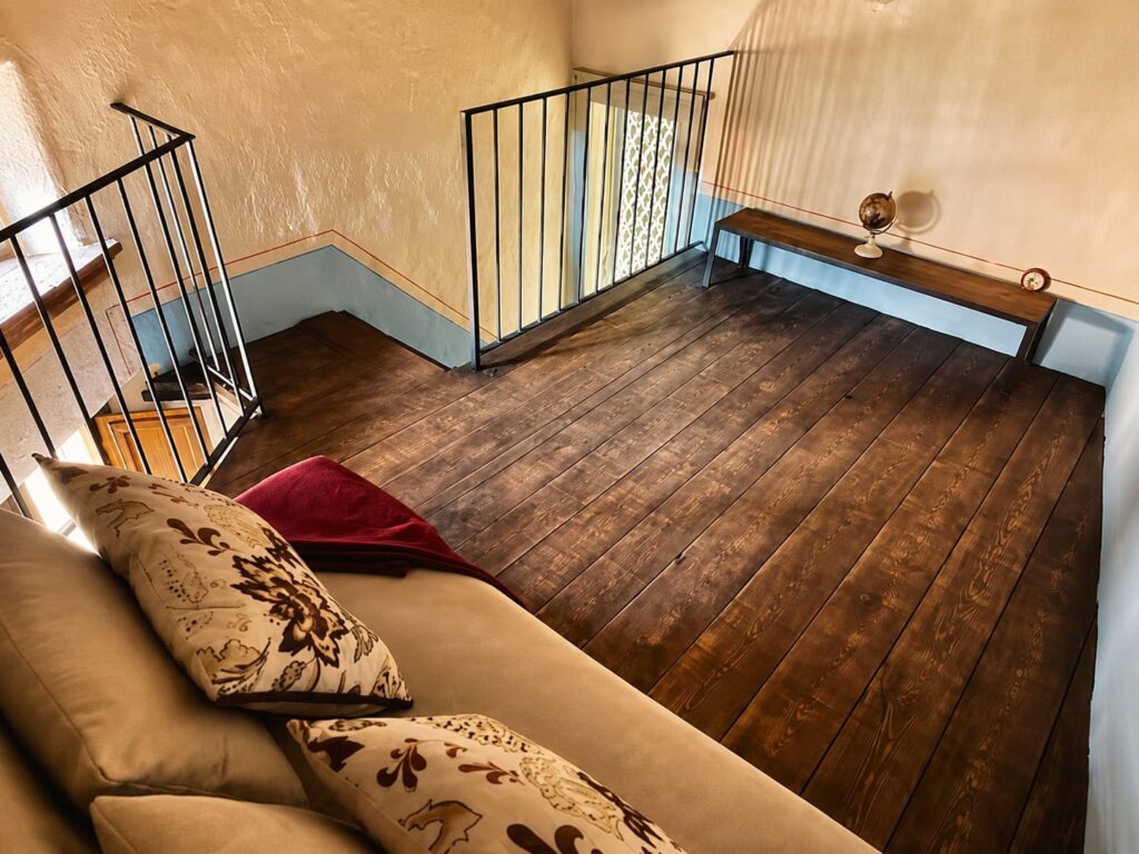 Bedroom with exposed beams and natural materials in a Borgo Braila apartment, Borgo Braila