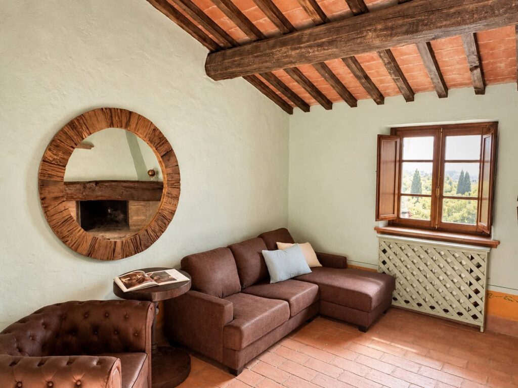 Living room with a leather corner sofa and round mirror in the La Dimora del Levante apartment, Borgo Braila, Umbria