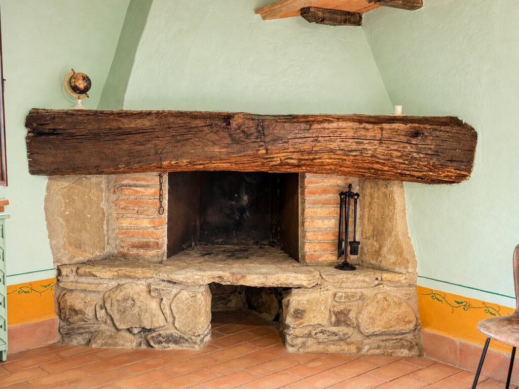Stone fireplace with a massive timber lintel in the La Dimora del Levante apartment, Borgo Braila, Umbria
