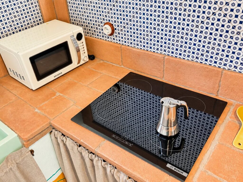 Induction hob with a moka pot on the terracotta counter in the La Dimora del Levante apartment, Borgo Braila, Umbria