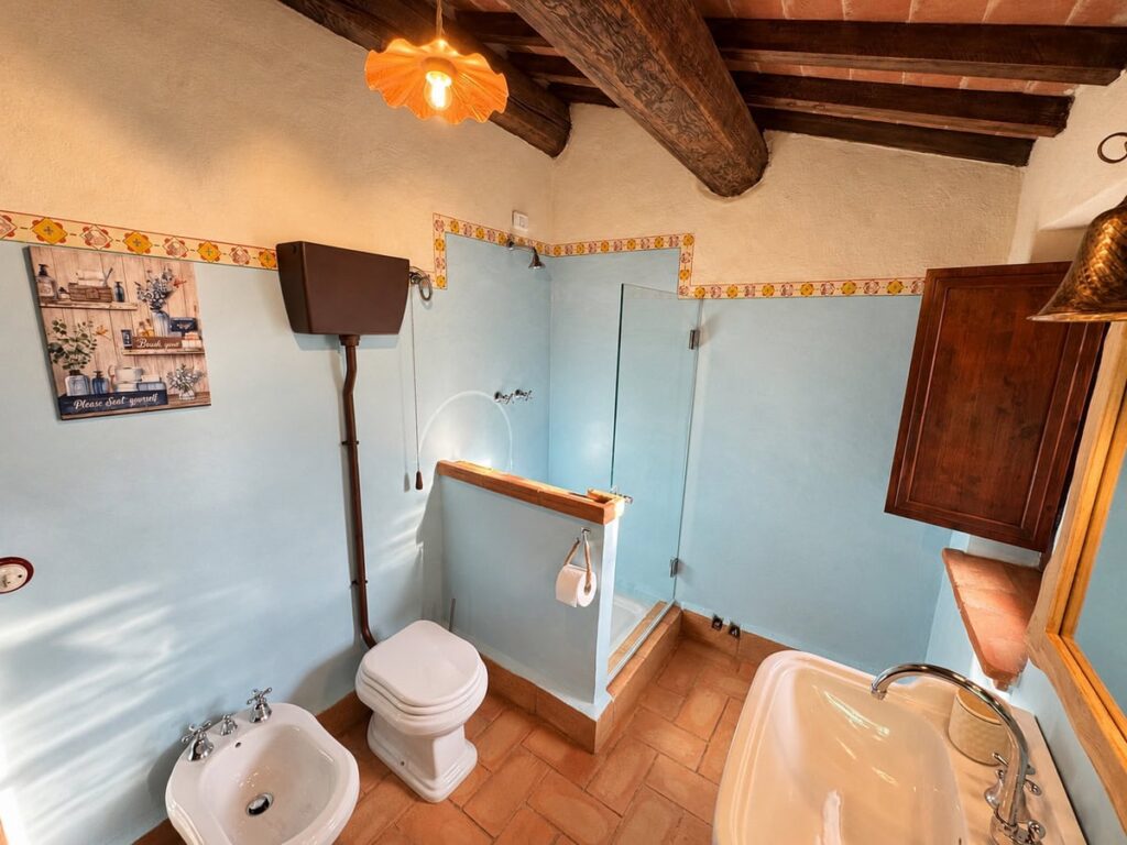 Bathroom with pale blue walls and a bathtub in the La Dimora del Levante apartment, Borgo Braila, Umbria