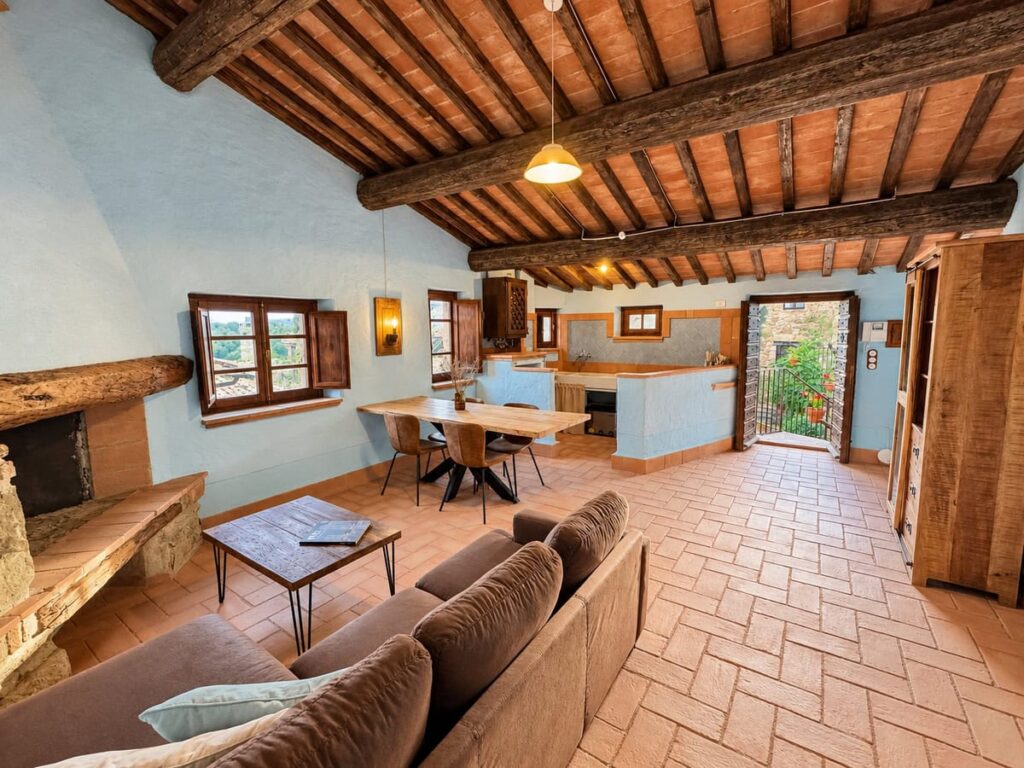 Living room with a stone fireplace and dining area in the La Casa Nobile apartment, Borgo Braila, Umbria